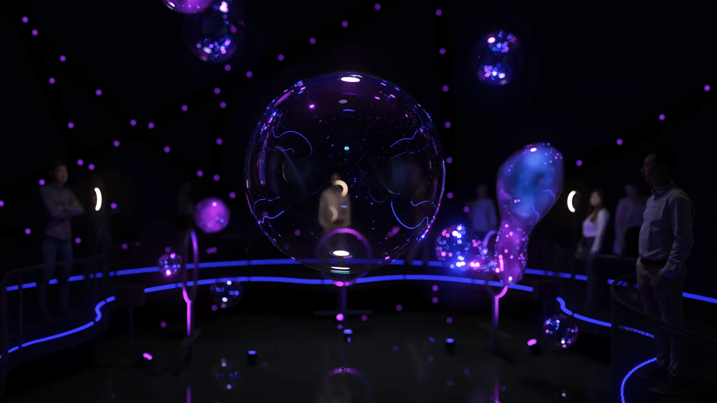 A large iridescent soap bubble glowing purple and blue at the centre of a darkened installation space, with smaller bubbles drifting around it and visitors watching from behind a curved, blue-lit railing.